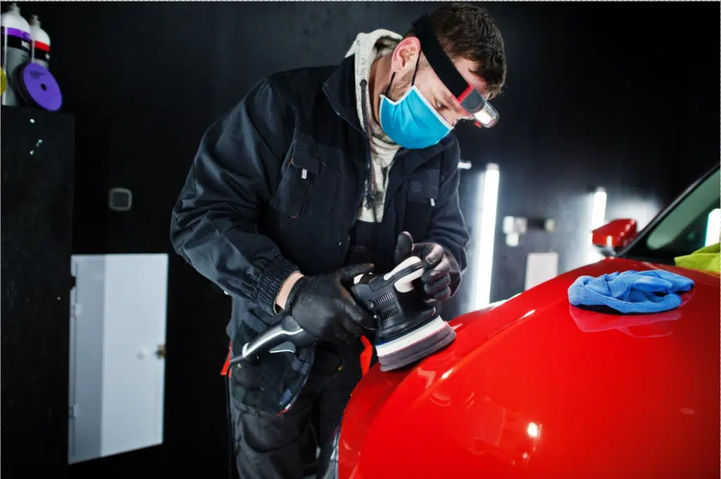 A skilled technician performing Car Dent Repair, carefully using a polishing machine on the hood to restore its smooth finish in a professional auto body shop in Las Vegas.