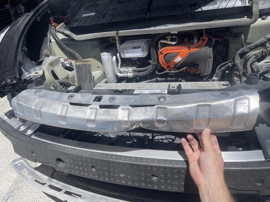 Deformed lower impact bar discovered behind the bumper of a collision-damaged Tesla Model Y