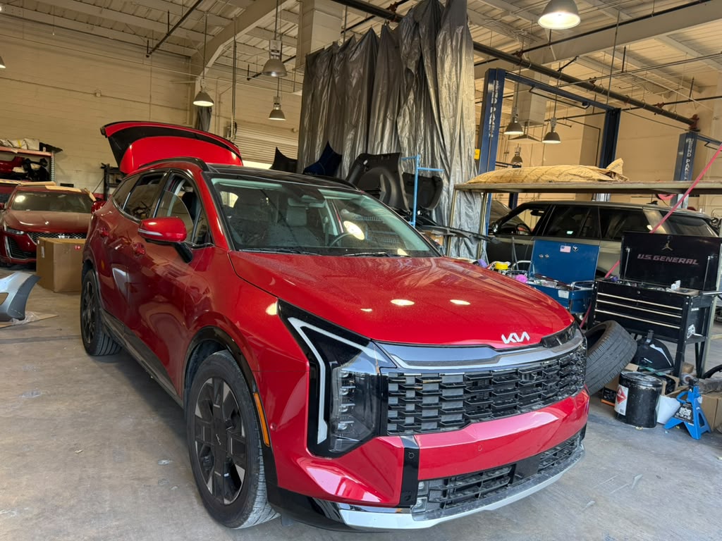 Second front angle of a red Kia SUV inside Universal Motorcars’ workshop, with its liftgate open.