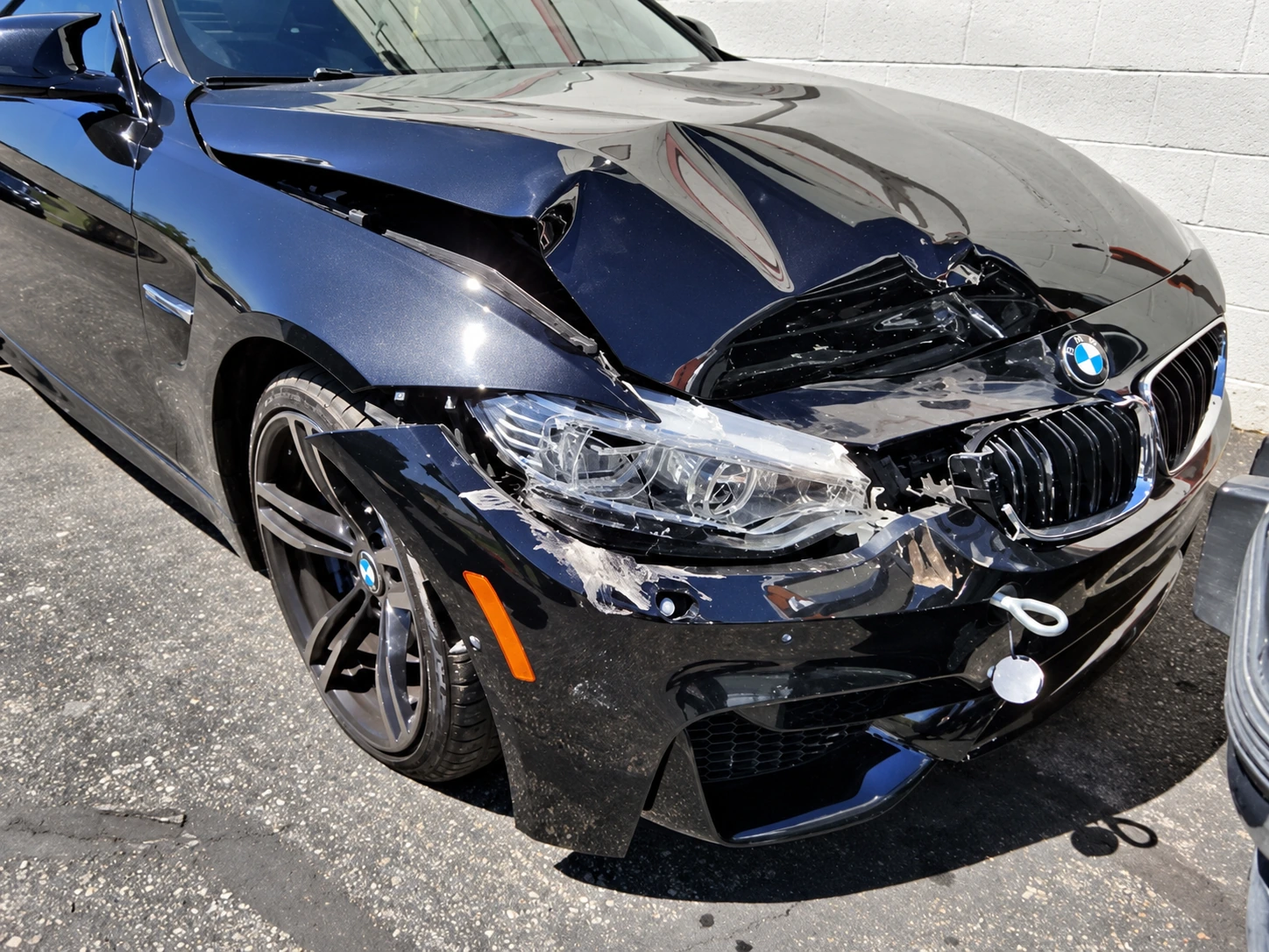 Blue BMW with a crumpled hood and damaged front bumper before collision repair