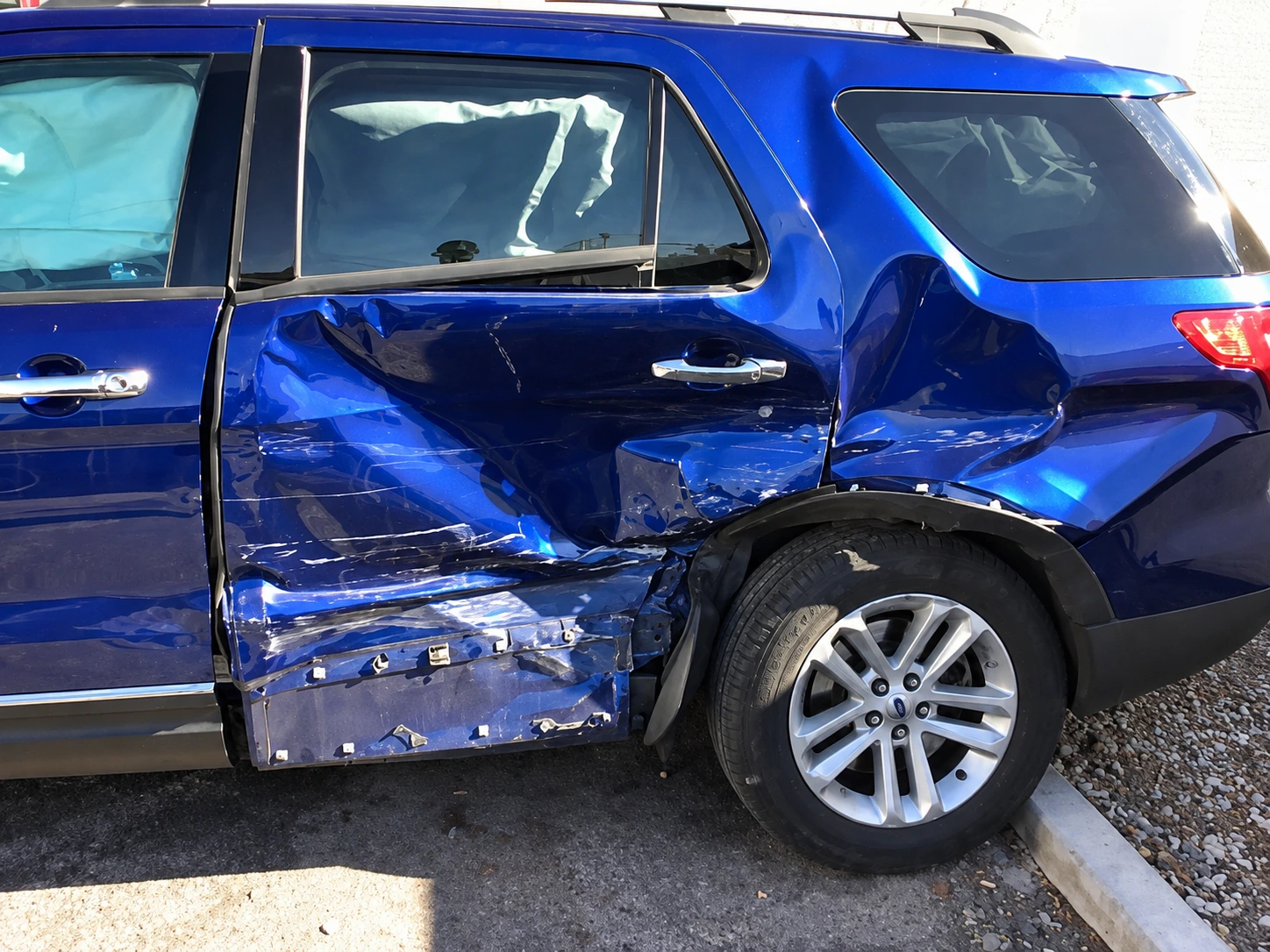 Blue Ford SUV with collision damage to the rear door and rear quarter panel before repair