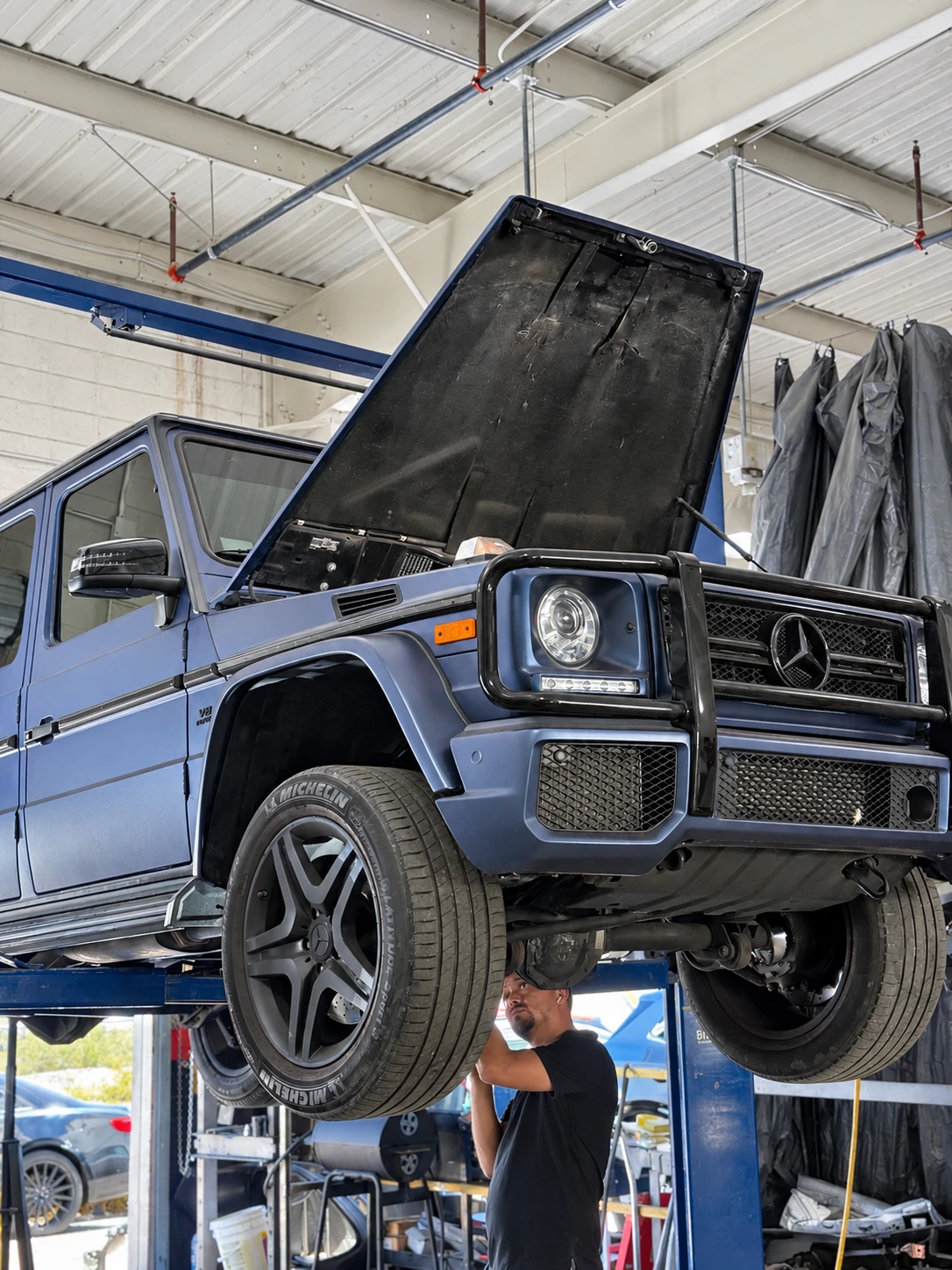 Blue Mercedes-Benz G-Class on a lift inside the Universal Motorcars workshop