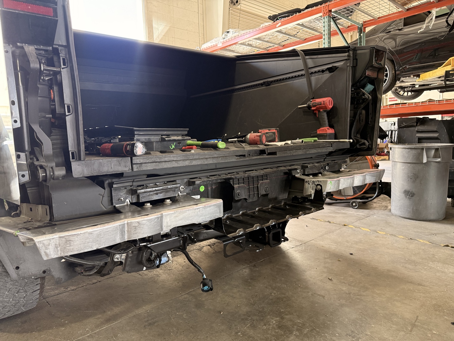 Cybertruck during repair with the tailgate and rear bumper cover removed, exposing the hitch and rear assembly