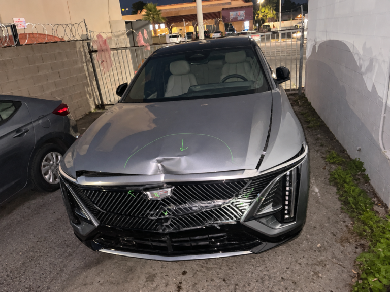 Silver Cadillac LYRIQ with a dented hood and damaged front grille