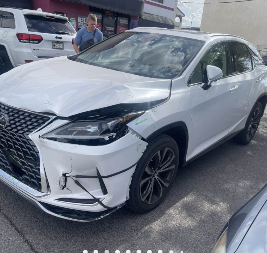 White Lexus SUV with cracked front bumper cover and damage around the headlamp and hood edge