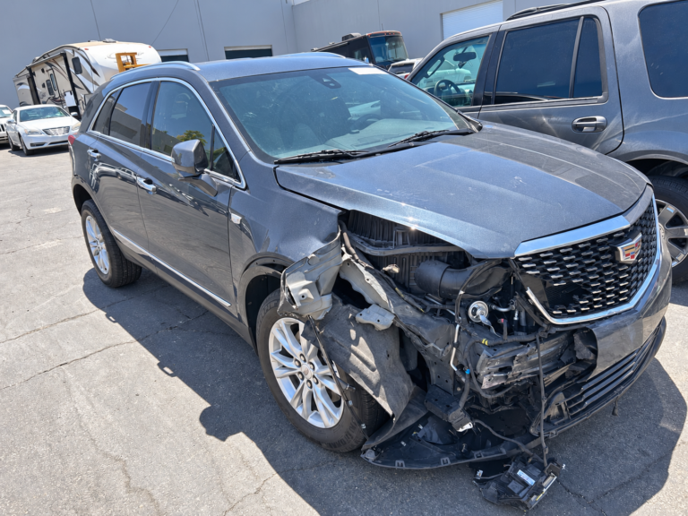 Cadillac SUV with front-right collision damage and exposed headlamp and bumper areas