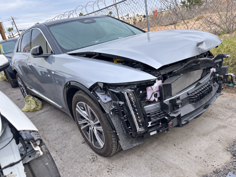 Silver Cadillac LYRIQ with front bumper components removed, showing the underlying repair area