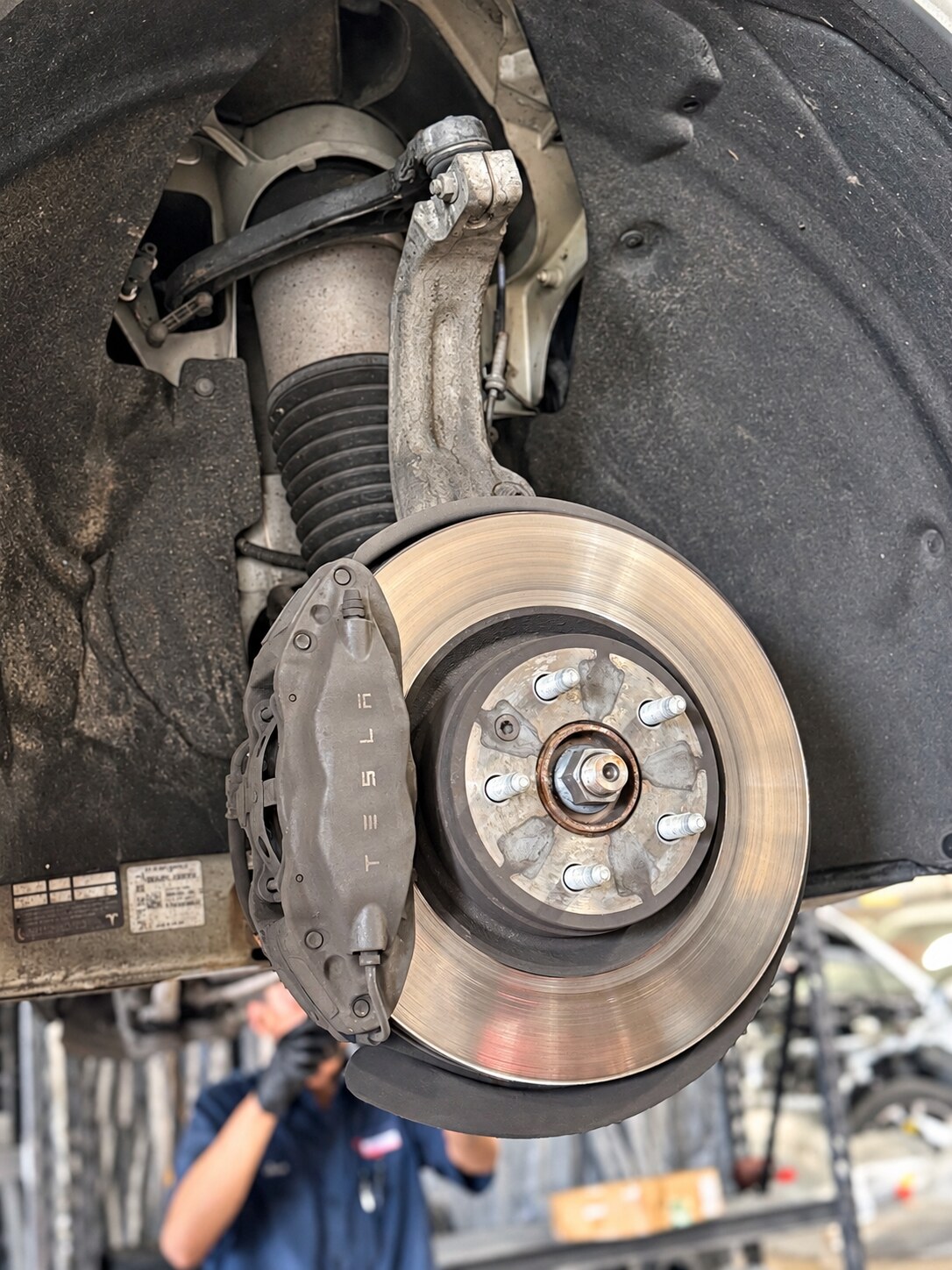 Air-spring assembly and suspension components above an exposed brake rotor and caliper.