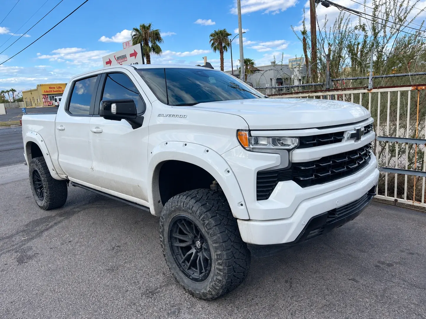 White Chevrolet Silverado pickup with visible marks on its front door.