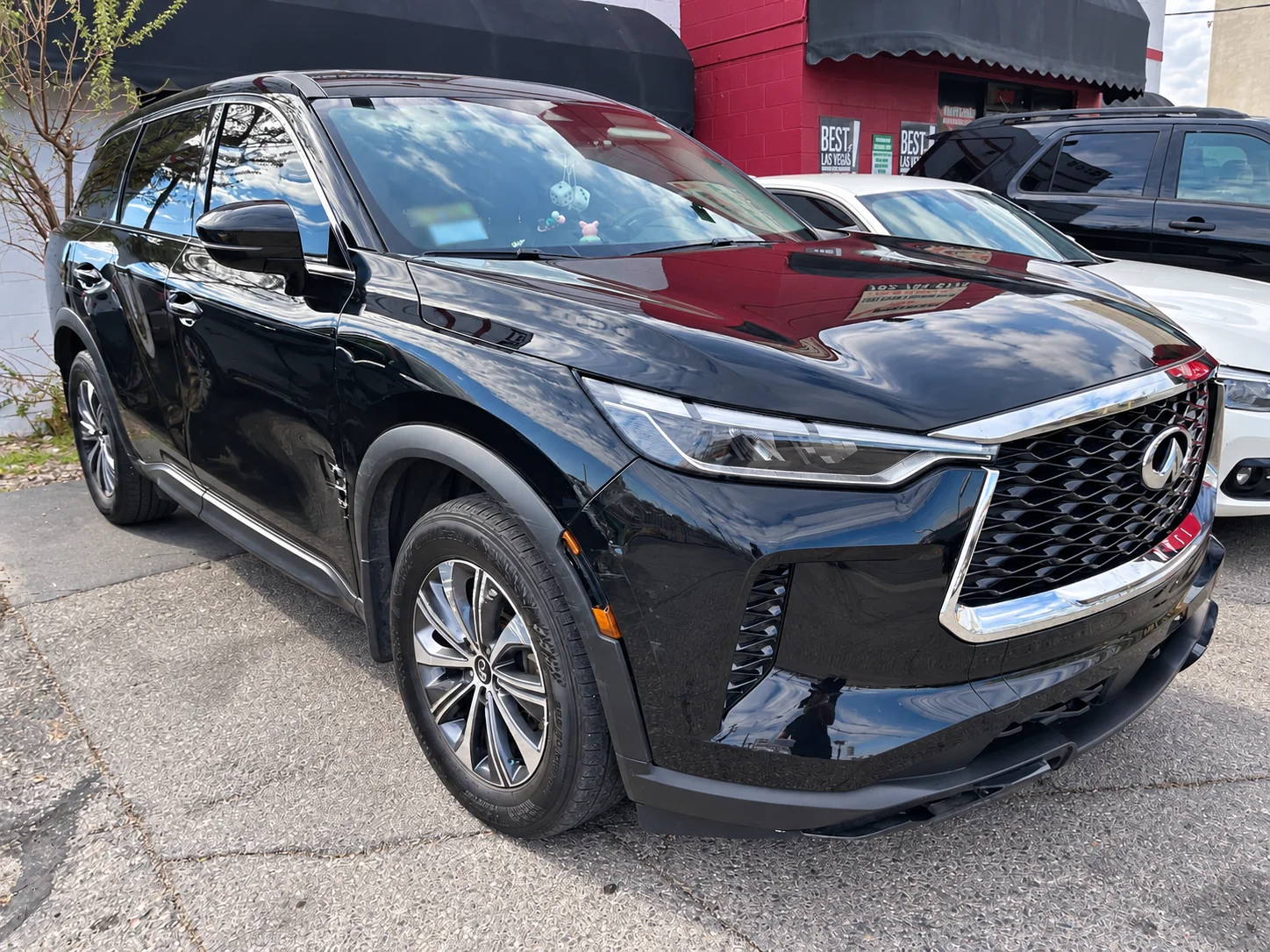 Black INFINITI SUV viewed from the front passenger side, showing the hood, fender and doors.