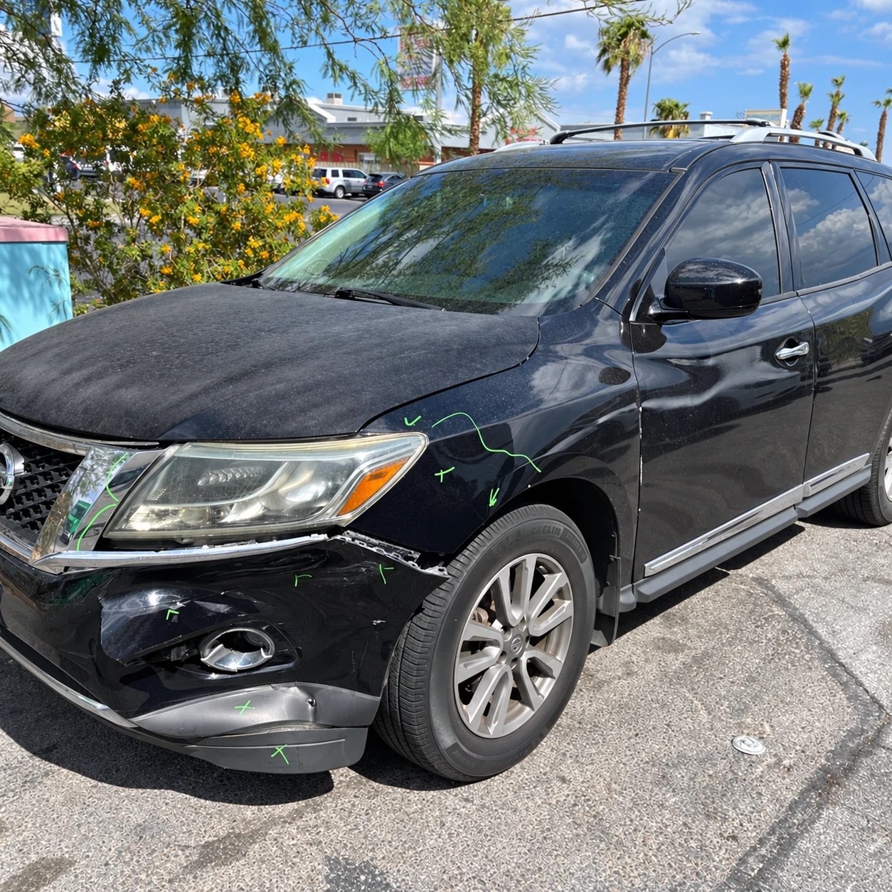 Black Nissan Pathfinder with front bumper separation and fender damage at Universal Motorcars in Las Vegas.
