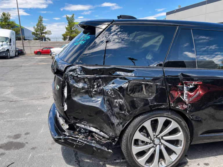 Black Range Rover with rear-quarter and rear-door damage and exposed rear-bumper components.