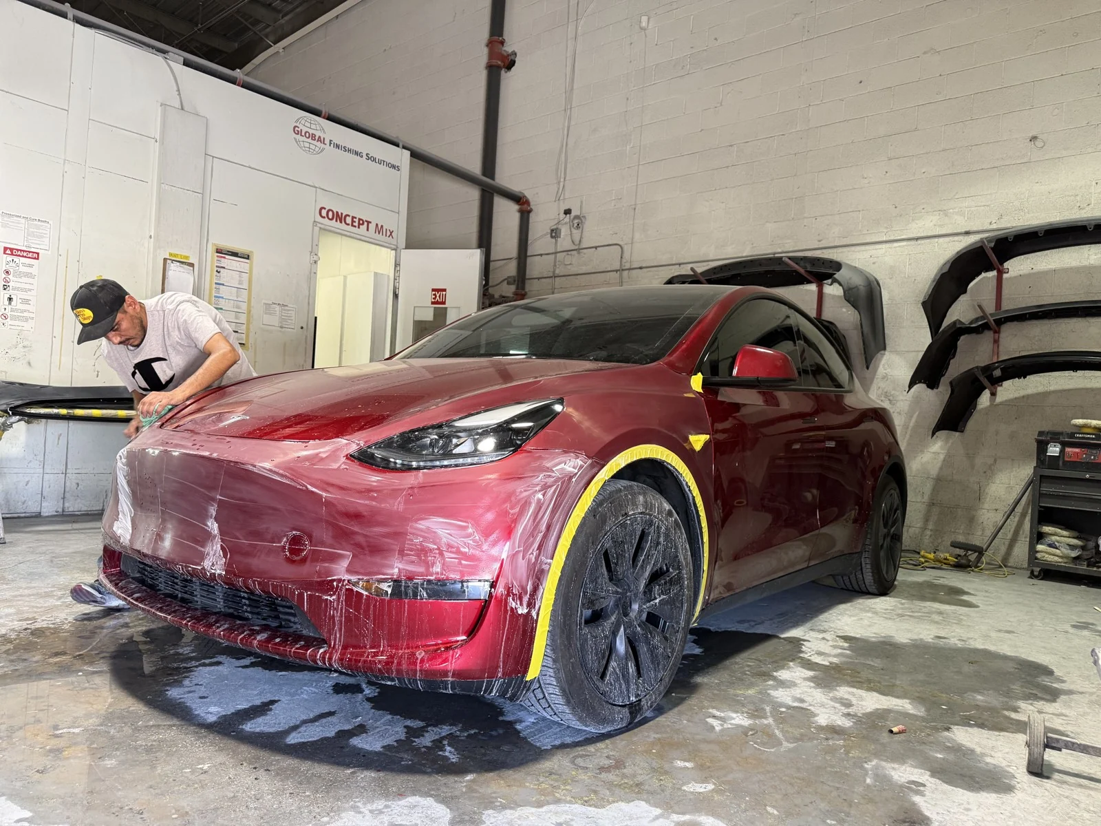 Universal Motorcars technician working on the paint finish of a red Tesla Model Y