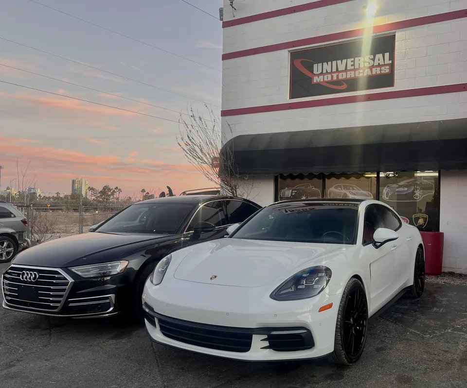 White Porsche Panamera and black Audi sedan at dusk