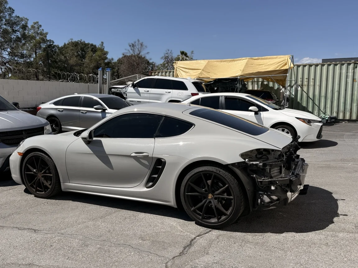 Silver Porsche Cayman with rear bumper cover and rear lamps removed, exposing mounting areas and components