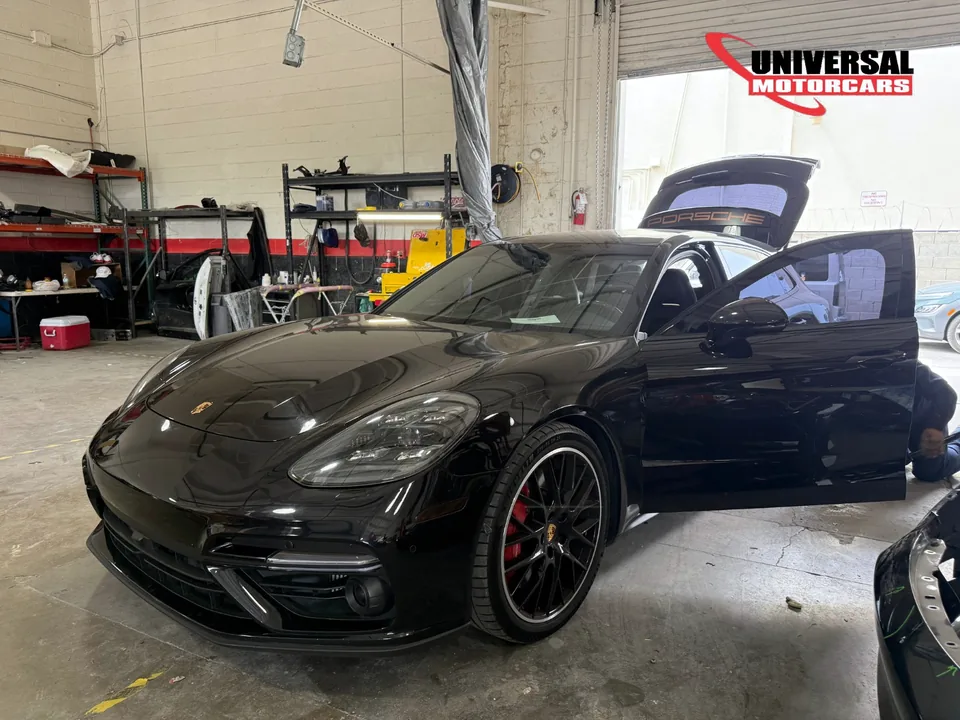 Black Porsche Panamera inside the workshop with a door and liftgate open