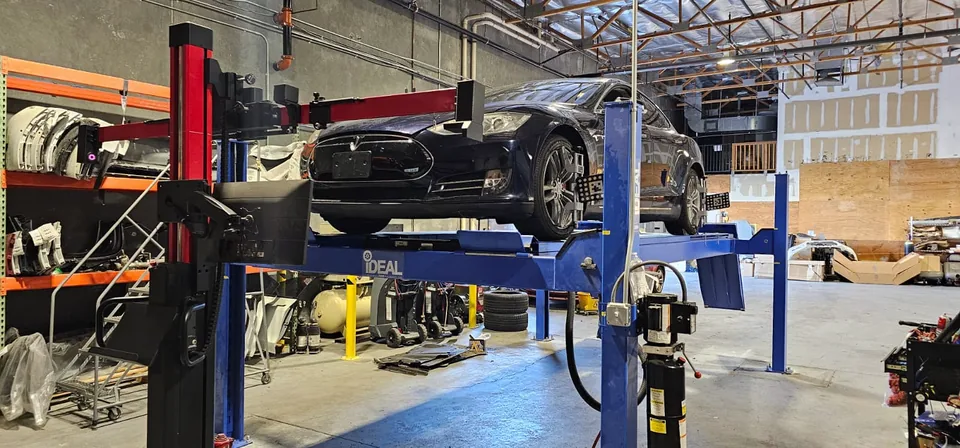Dark Tesla Model S positioned on an alignment rack