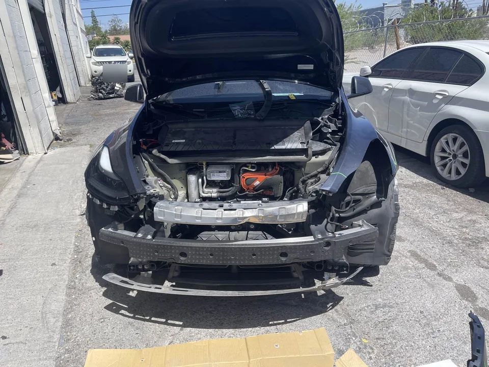 Tesla Model Y with the front bumper removed during collision repair assessment