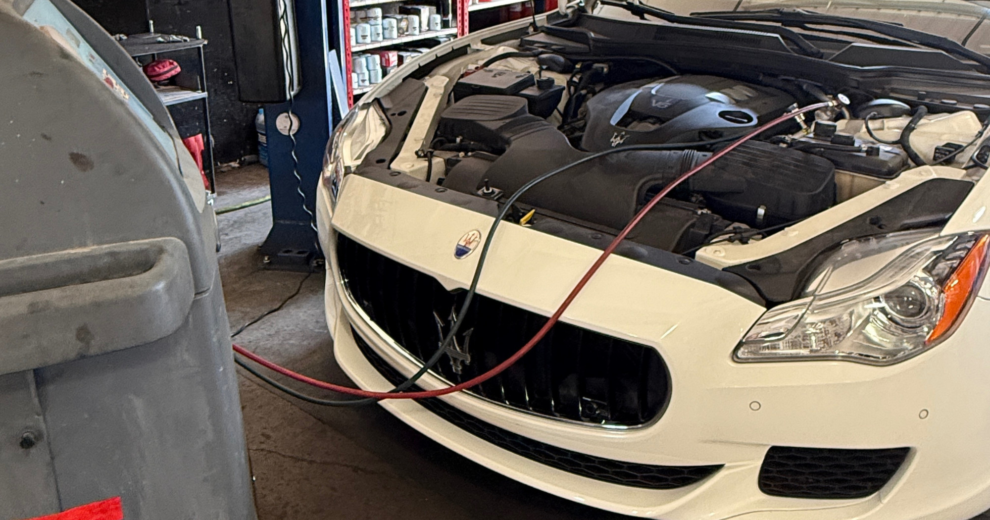 Maserati with its hood open and air-conditioning service hoses connected