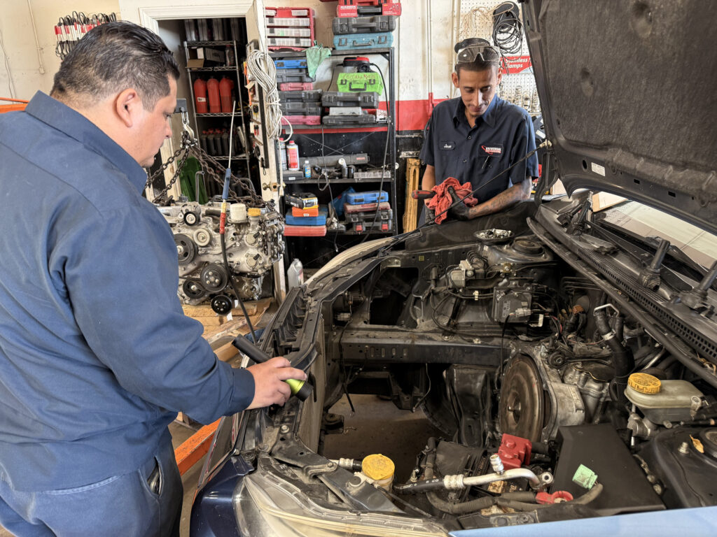 Engine work beside an open engine bay and a removed engine at Universal Motorcars