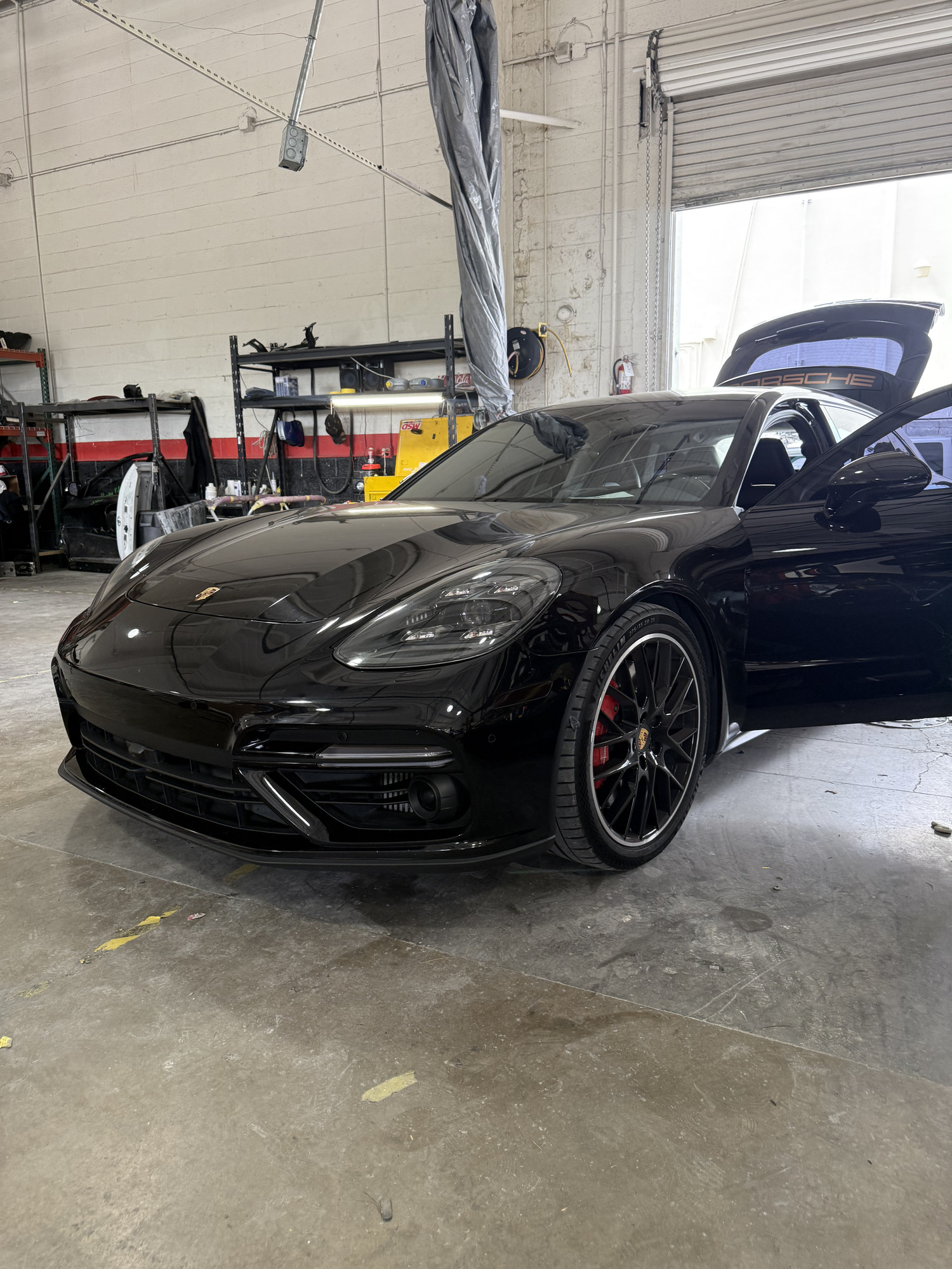 Black Porsche Panamera inside a Universal Motorcars workshop with its doors and hatch open