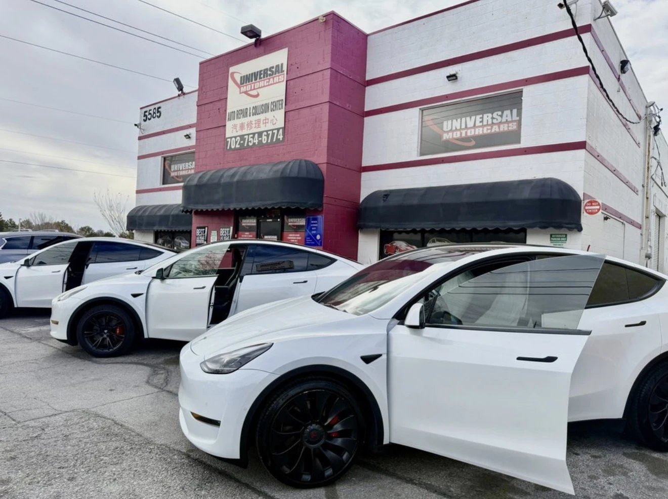 Three white Tesla Model Y vehicles outside Universal Motorcars on Spring Mountain Road in Las Vegas