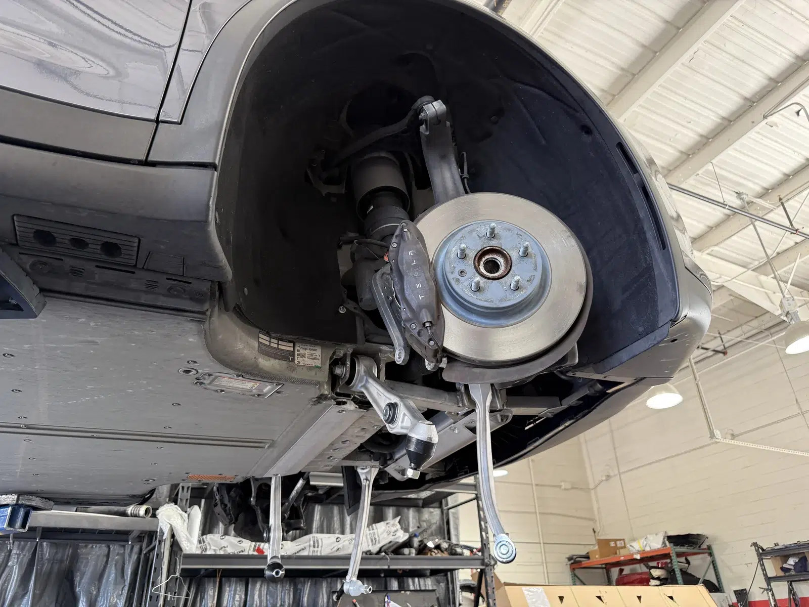 Tesla brake rotor and caliper exposed with the wheel removed.