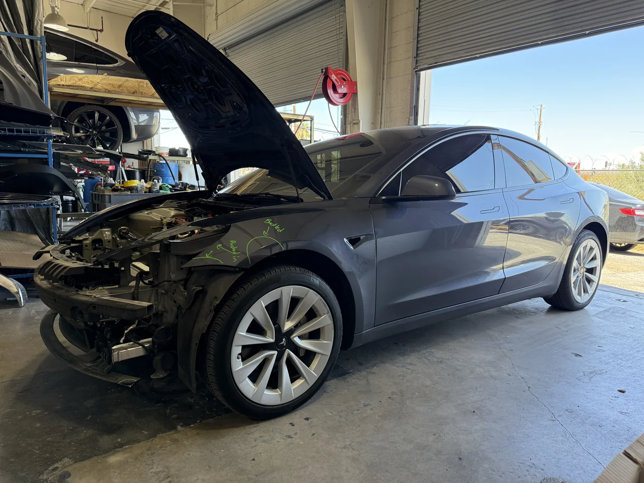 Gray Tesla with its front bumper removed and front-end components exposed at Universal Motorcars in Las Vegas.