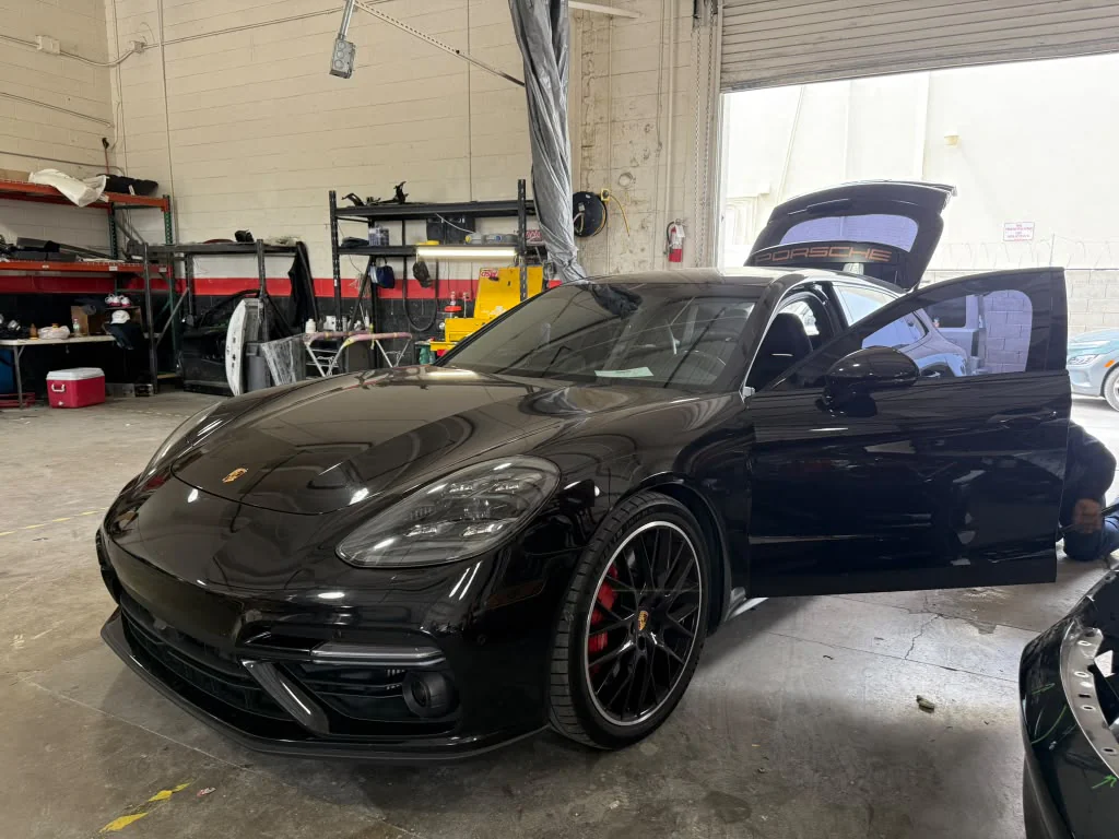 Black Porsche in a Universal Motorcars workshop bay with its door and rear hatch open
