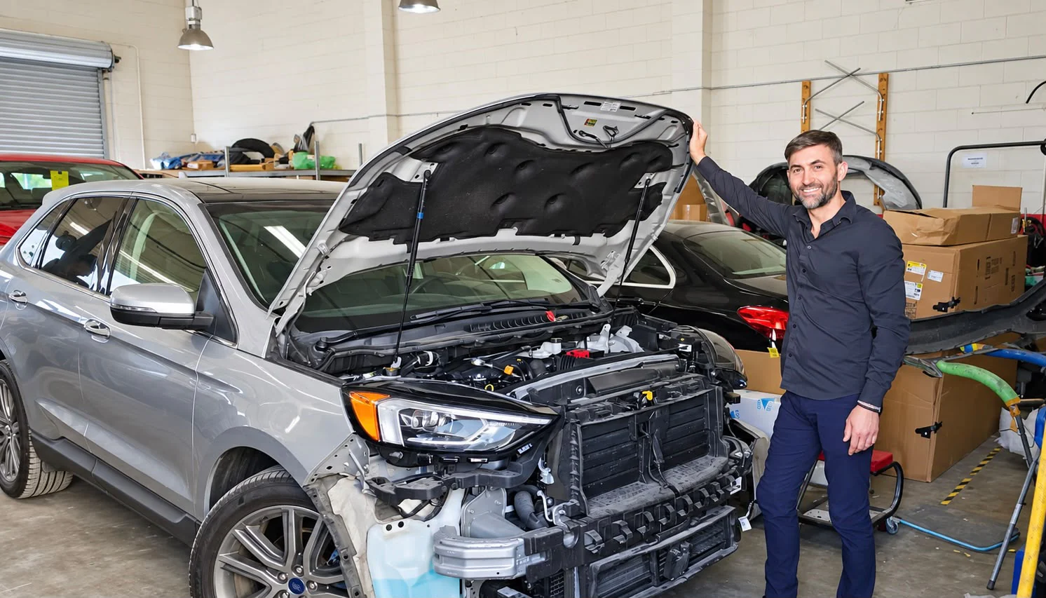 Universal Motorcars team member beside a car with its hood open in the Las Vegas repair shop